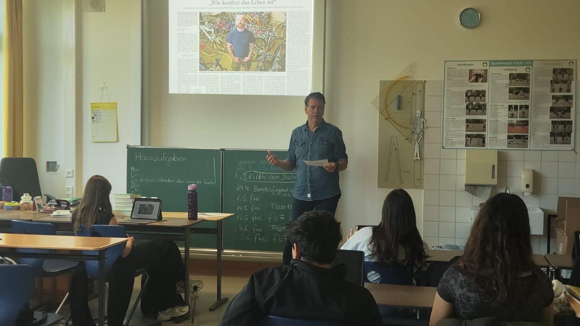 Journalist Marc Prams (Saarbrücker Zeitung) im Klassenzimmer vor einer Schulklasse 