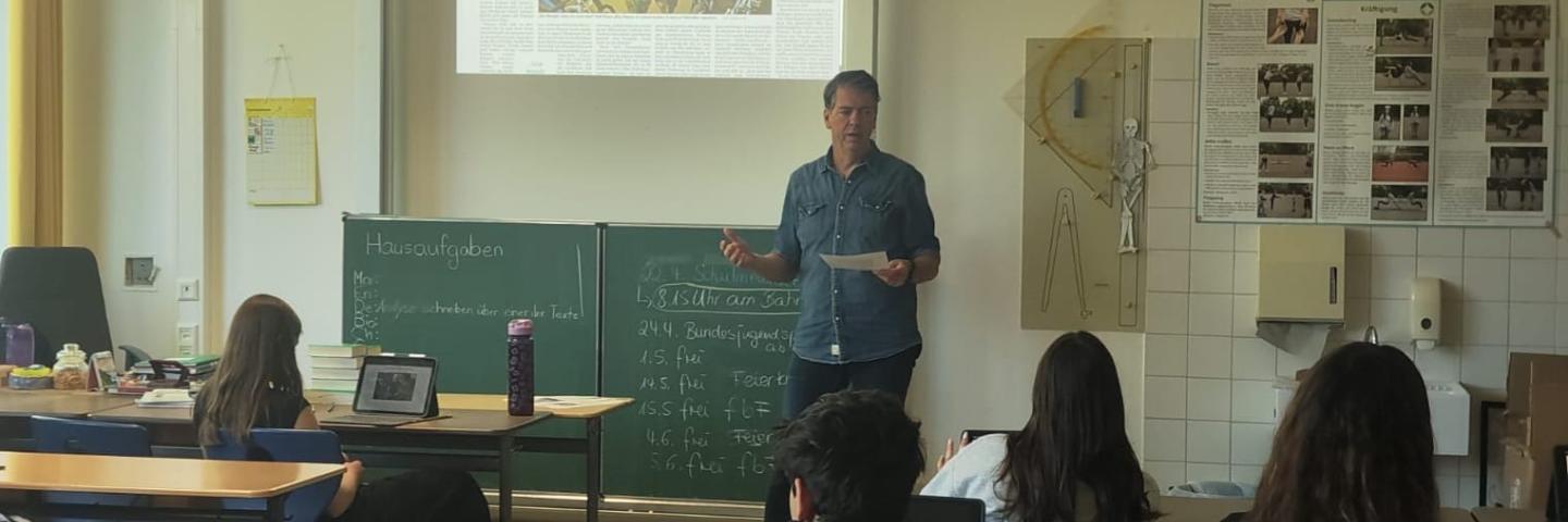 Journalist Marc Prams (Saarbrücker Zeitung) im Klassenzimmer vor einer Schulklasse 